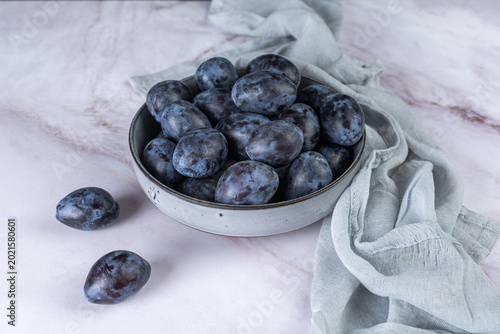 Fresh plums in a clay bowl.