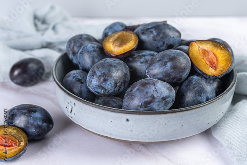 Natural vegan snack, plums in ceramic plate. Healthy food concepts and autumn harvest backgrounds.