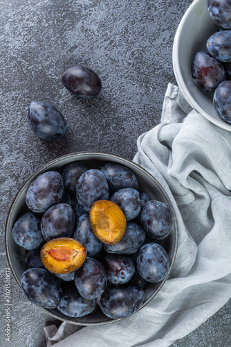 Sweet plums and halves on marble surface. Minimalist food photo. Healthy food concepts and autumn harvest backgrounds