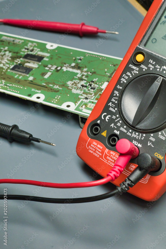 Fototapeta premium Orange digital multimeter with probes and pcb
