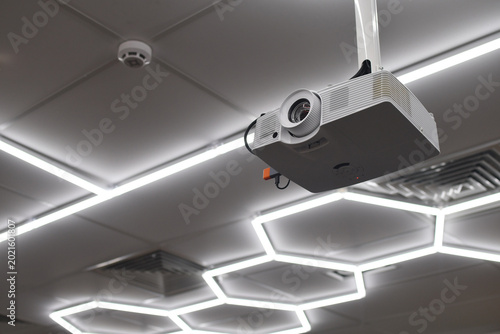 Front view of ceiling mounted digital projector in modern office or conference room