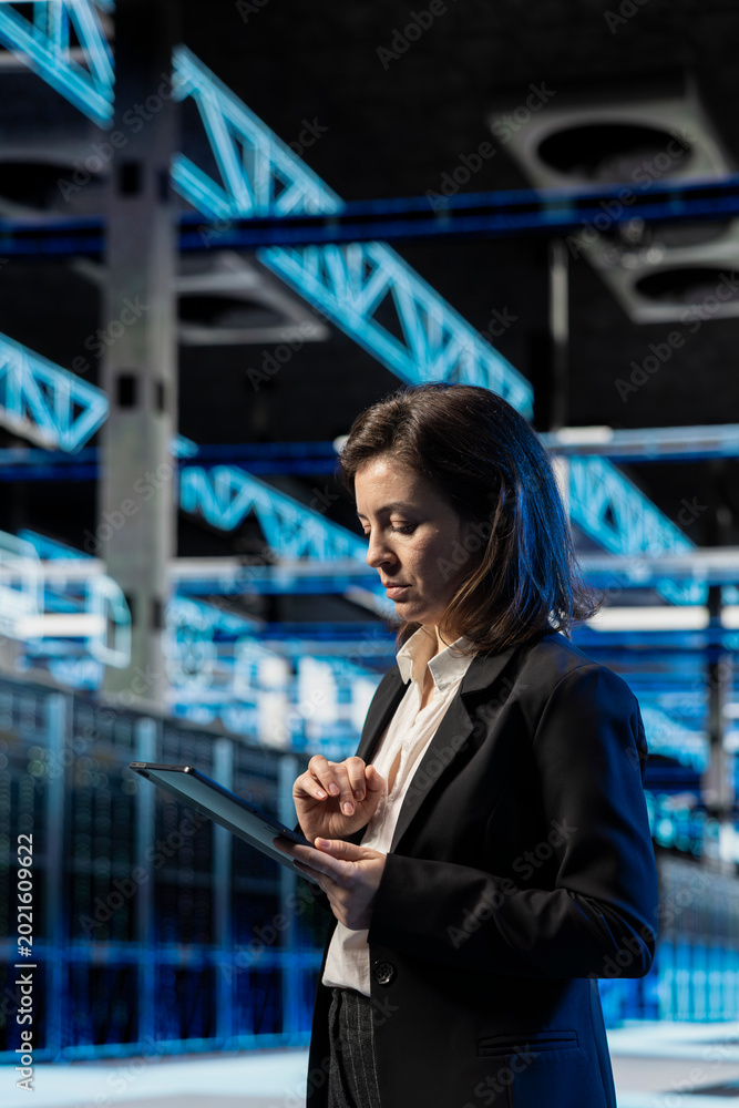 Fototapeta premium Data center software developer using tablet to inspect infrastructure rackmounts, updating network systems. IT expert using device to ensure stable server room operations, overseeing equipment rigs