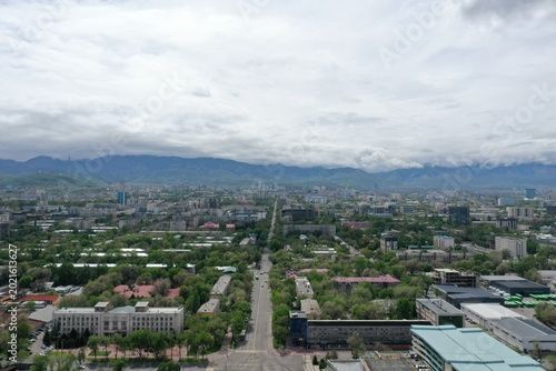 Aerial view of urban cityscape of Almaty with distant mountains under cloudy skies, Kazakhstan