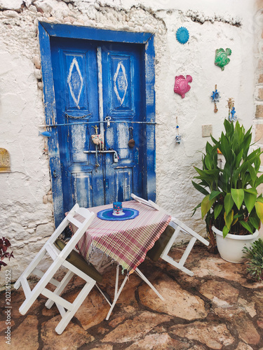 Rustic blue wooden door with decorative fish and street cafe in Kalkan Turkey
