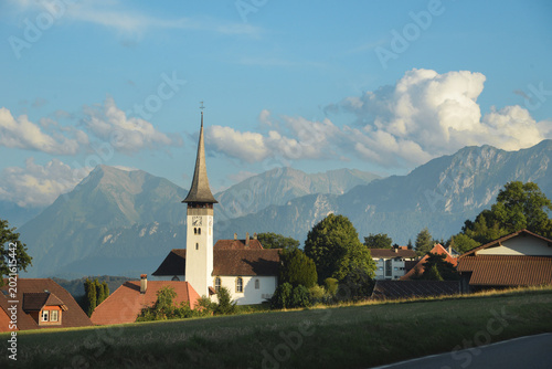 Принти на полотні Picturesque alpine village with a church spire against a mountain backdrop