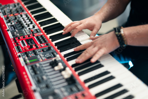 Close-up of musician's hands playing a red professional electronic keyboard synthesizer