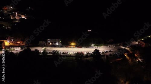 Charming night scene showcases peaceful village illuminated by soft lights and filled with parked cars under a starlit sky