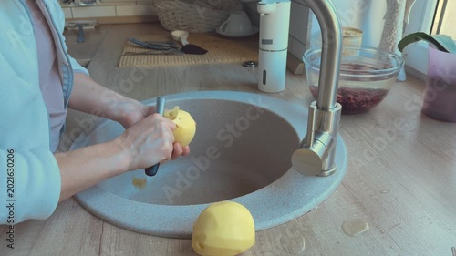Potatoes peeled in sink removing skin preparing vegetables for cooking. 
