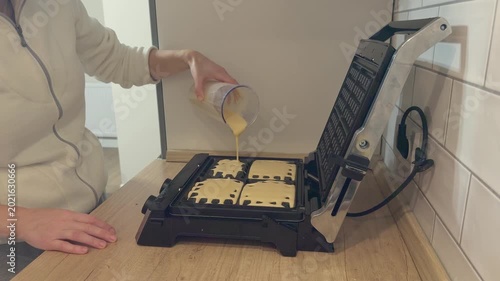 Open waffle maker filled with batter cooking fresh waffles in home kitchen breakfast preparation.