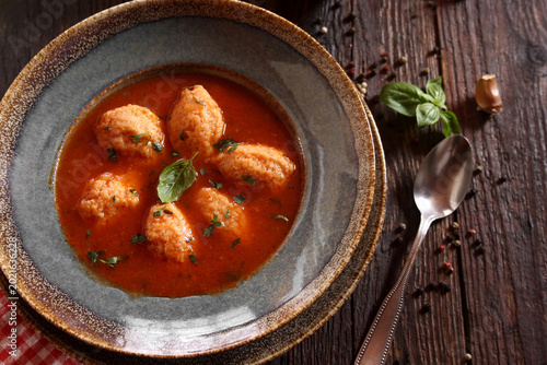 Foto Tomato soup with semolina dumplings on a wooden background