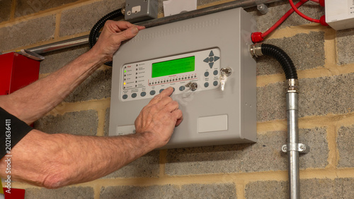 Foto Fire alarm engineer investigating a fault on a fire protection system during planned maintenance, ensuring the safe and reliable operation of industrial fire suppression equipment