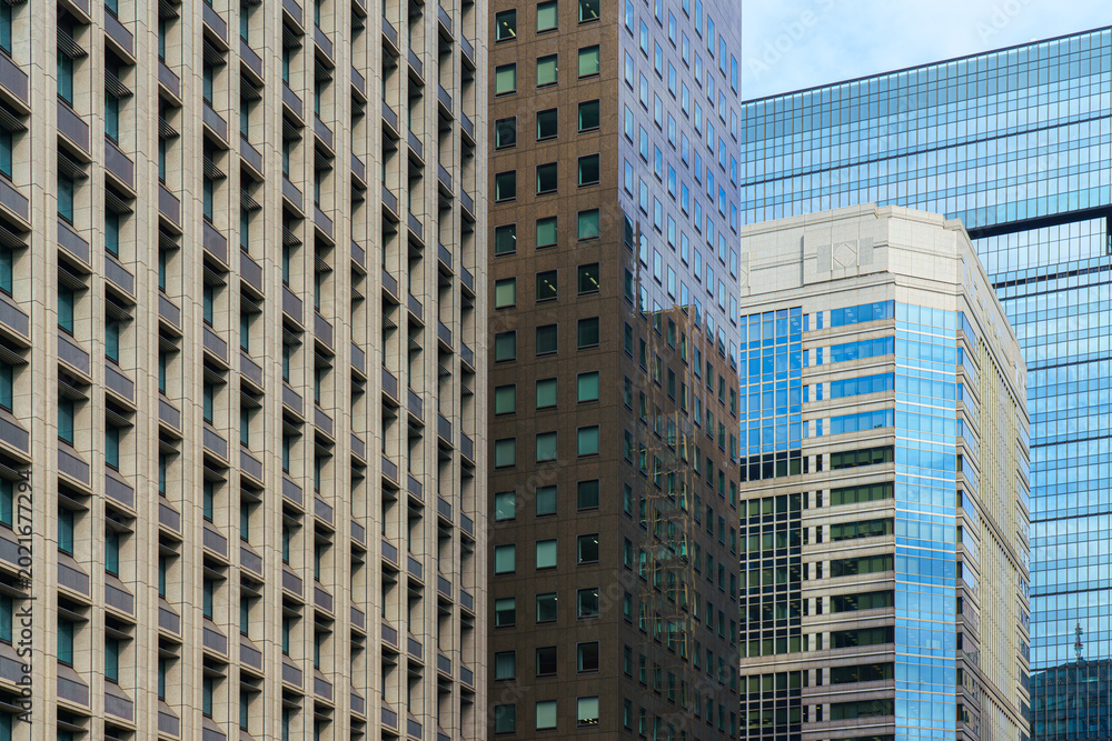 Obraz premium Tokyo, Japan - Oct 1 2024, A panoramic view of the glass facades of skyscrapers in Chiyoda district, with a blue sky and clouds in the background, at daytime,Tokyo, Japan