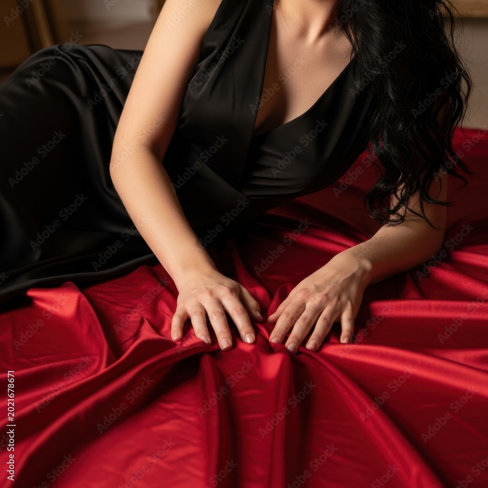 Naklejka premium Woman in Black Dress on Red Satin Sheets.