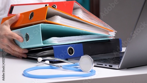Fotografie Healthcare professional balancing a heavy stack of patient medical records and f