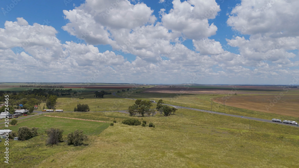 Fototapeta premium Aerial View of Rural Farmland with Highway and Fluffy Clouds