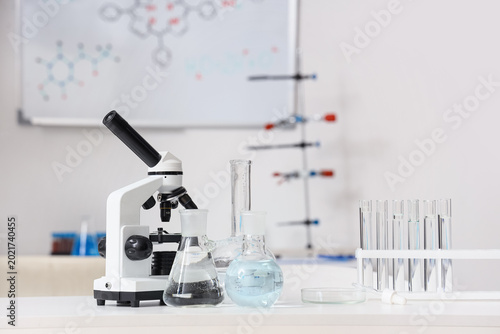Microscope with test tubes and flasks of water samples on table in research l...