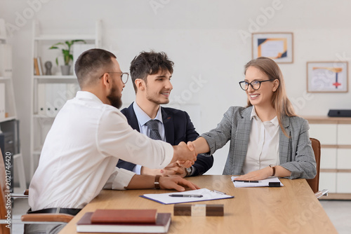 Foto Male business mediator shaking hands with clients at table in office