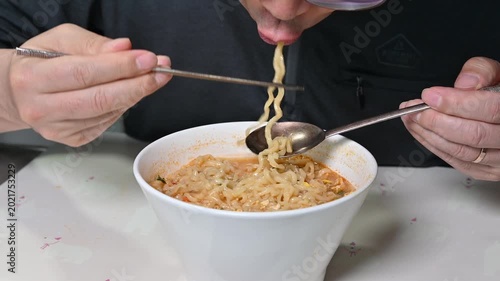 close up of a man eating delicious korean instant noodles, slurping ramen with chopsticks and spoon