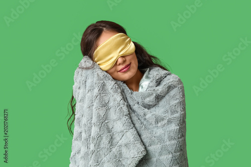 Beautiful young happy Asian woman with warm soft plaid and sleeping mask on g...