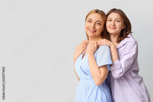 Beautiful mature woman with her daughter on grey background. Mother's Day cel...