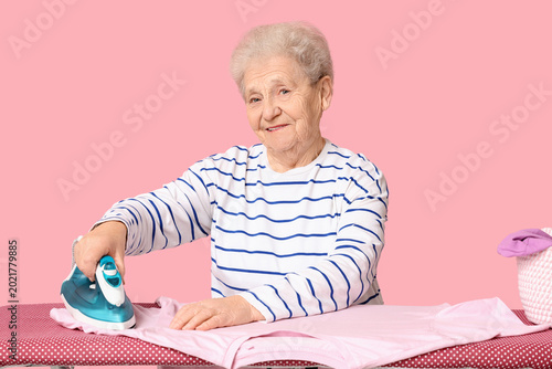 Happy senior woman ironing ...