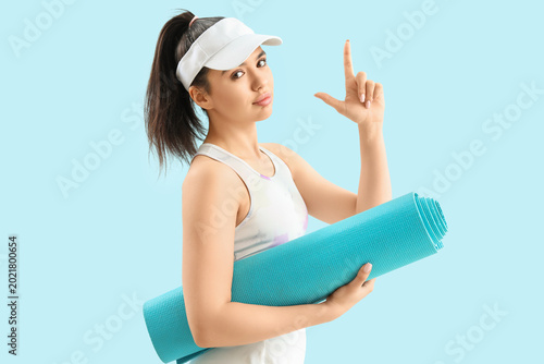 Valokuva Sporty young woman with mat showing loser gesture on blue background