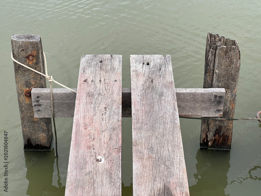 Obraz premium a vertical shot of a wooden pier with a fishing boat in the lake