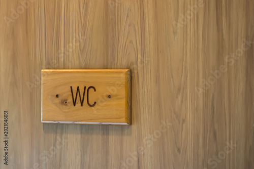 WC Sign on Wooden Door: A close-up shot of a wooden door with a wooden WC sign, signifying a restroom entrance, simplicity, and natural aesthetic