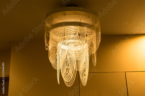 Elegant Chandelier: A close-up shot of a modern chandelier, its intricate design illuminated against a warm background, radiates sophistication and artistic flair. 