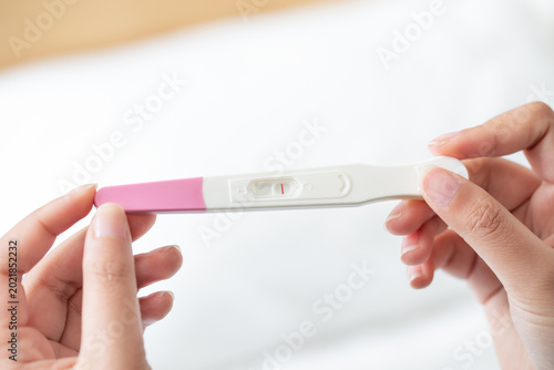 Fotografie Closeup of a woman's hand holding up a pregnancy test kit with a negative result