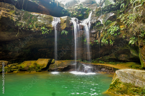Photos Scenic tropical waterfall cascading over moss-covered rocks into a crystal-clear pool, surrounded by lush green forest vegetation and serene natural landscape in The Garden of Caves, Meghalaya