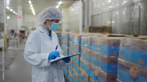 Quality Assurance in Production: A dedicated food industry professional meticulously inspects packaged products in a sterile production facility, ensuring adherence to quality control standards. 