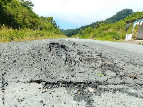Damaged asphalt road surface with cracks and potholes, showing poor infrastructure condition and transportation safety issues. Realistic urban street texture ideal for construction, maintenance, repai