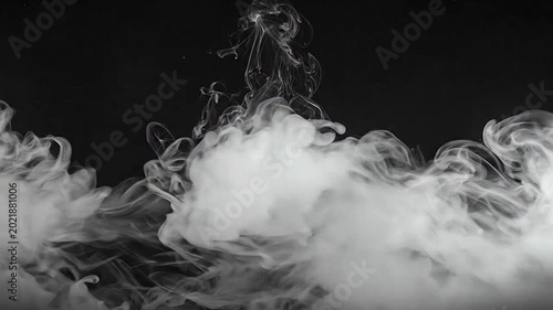 Dense white smoke billows across a solid black background in a studio setting
