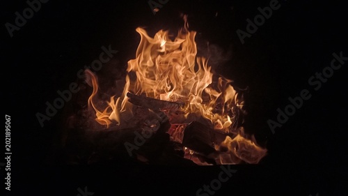 Fotografie High angle view of a blazing campfire with orange flames and glowing embers against a dark night background