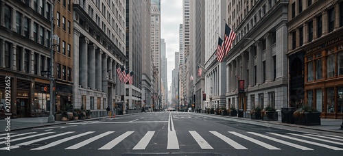 Empty New York City street with towering skyscrapers, American flags, and crosswalk on an overcast day