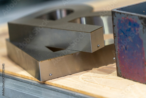 Foto Custom fabricated stainless steel channel letters and layered acrylic signage components displayed in a sign manufacturing workshop during production