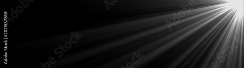 Fotografie Bright light rays shining from top corner on black background creating dramatic beam atmosphere