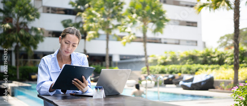 Canvastavla Professional businesswoman reviewing clipboard with laptop at luxury hotel pools