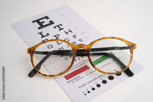 Photos Glasses on eye testing exam chart to check eyesight accuracy of reading