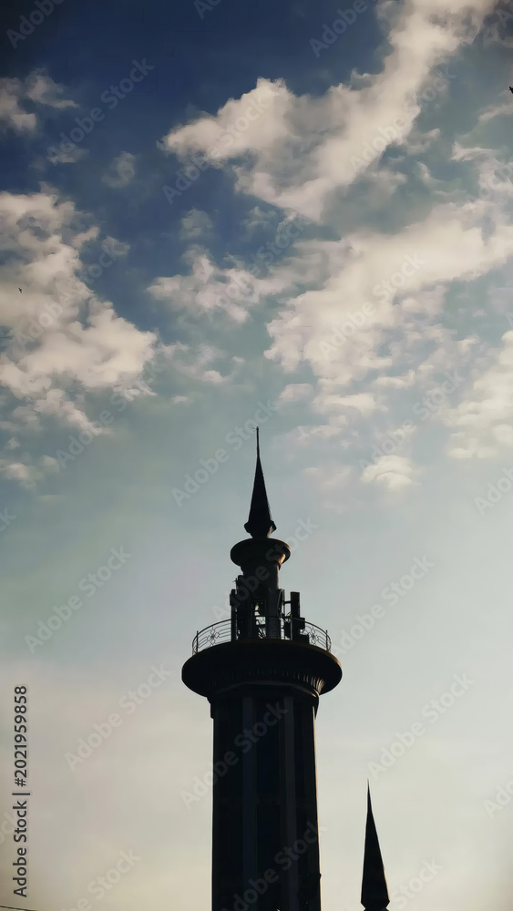 Obraz premium Silhouette Of Ornate Spire Tower Against Blue Sky With Soft Clouds At Sunset