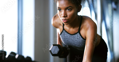 Fotografija Fitness, serious or woman in center with dumbbell, weightlifting power or renegade row in bodybuilding