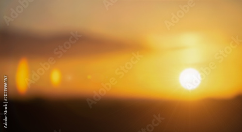 Фотография Abstract blurry sunset sky background with bright sun lens flare glowing orange