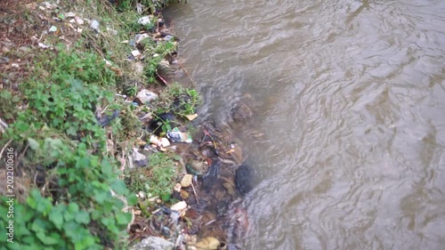 Polluted Riverbank with Trash and Dirty Water