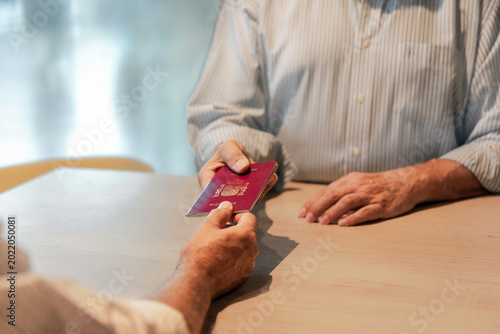 Close up of senior traveler handing over passport at an airport check-in counter