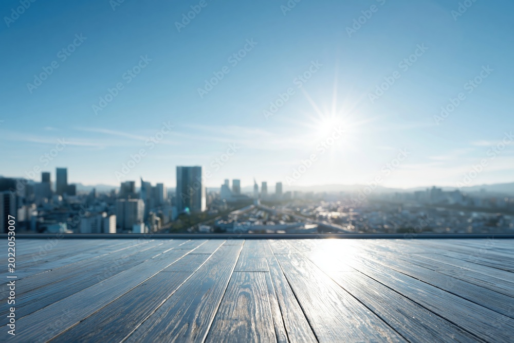 Fototapeta premium Sunlit Wooden Deck Overlooking a Blurry Cityscape with Modern Skyscrapers Under a Clear Blue Sky