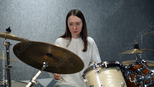 Obraz na plátně young woman playing drums in a studio, learning process, music