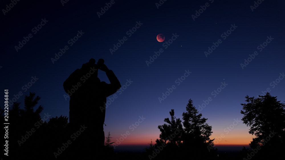 Fototapeta premium Amateur astronomer using binoculars for observing stars, planets, Moon and other celestial objects.