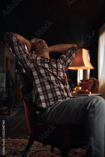 Man with headache, depression, sadness and loneliness sitting on a chair at home.