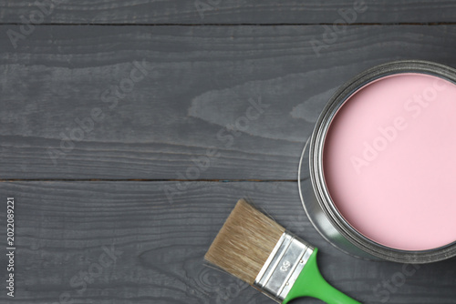 Iron can of bright paint and brush on gray wooden background, top view
